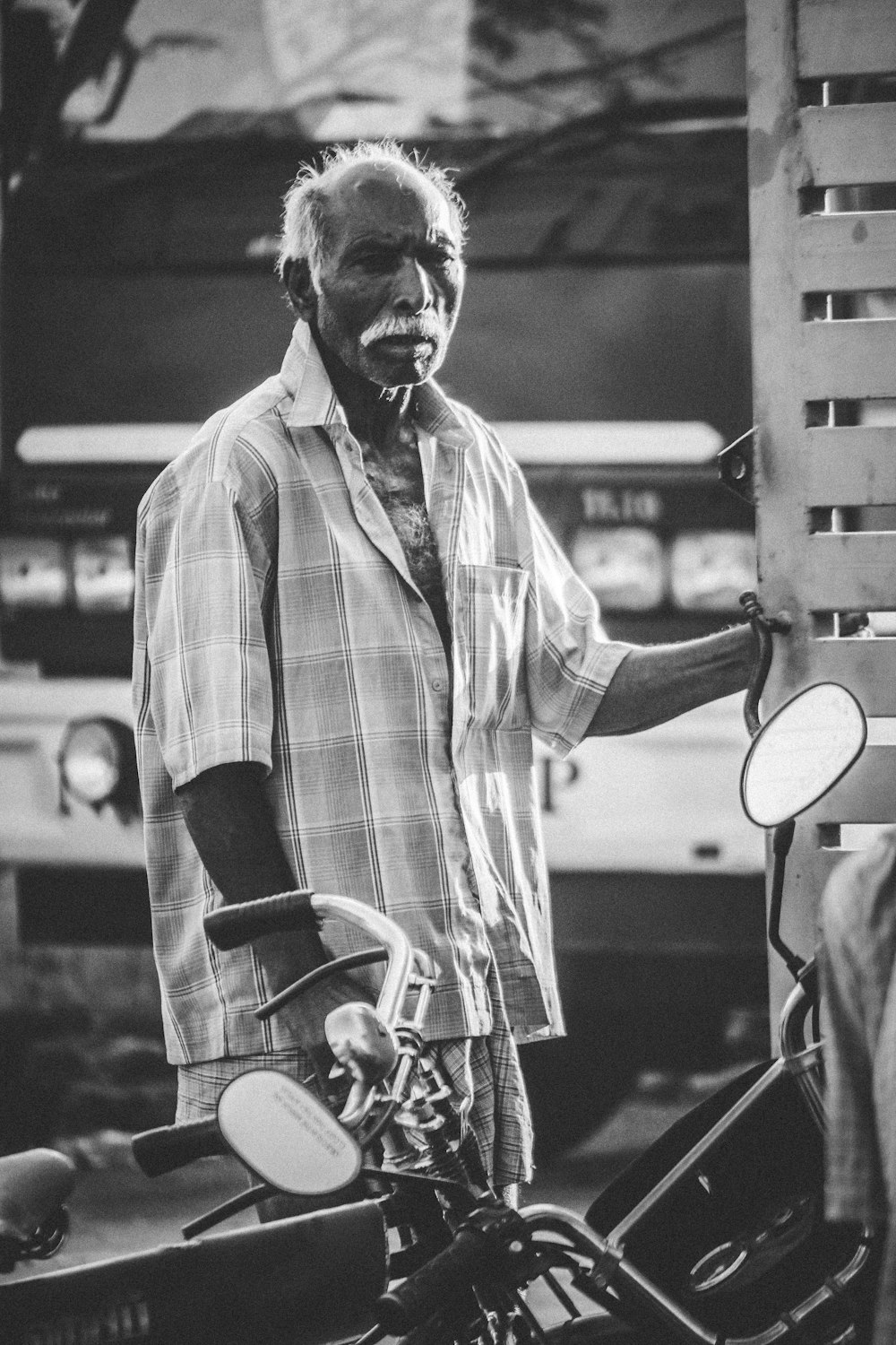 grayscale photography of a man near motorcycles