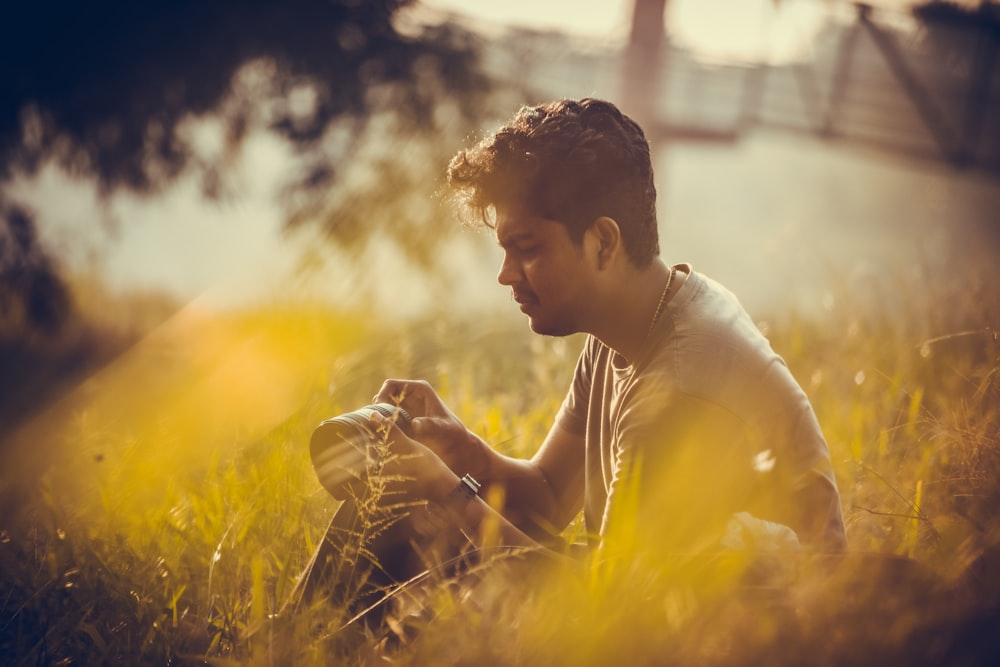 man in gray shirt sitting on grass