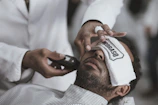 A barber applying a hot towel treatment to a relaxed customer.