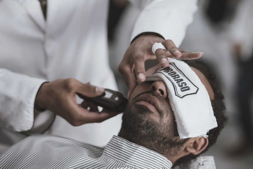 man shaving lying man