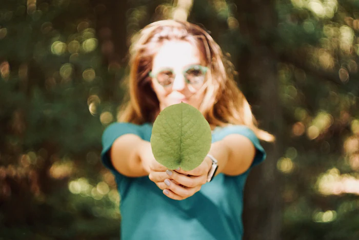 Mujer sosteniendo una hoja verde, conexión con la naturaleza