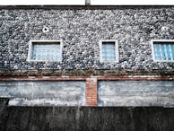 Exterior facade featuring a mix of stone and resin finishes under daylight.