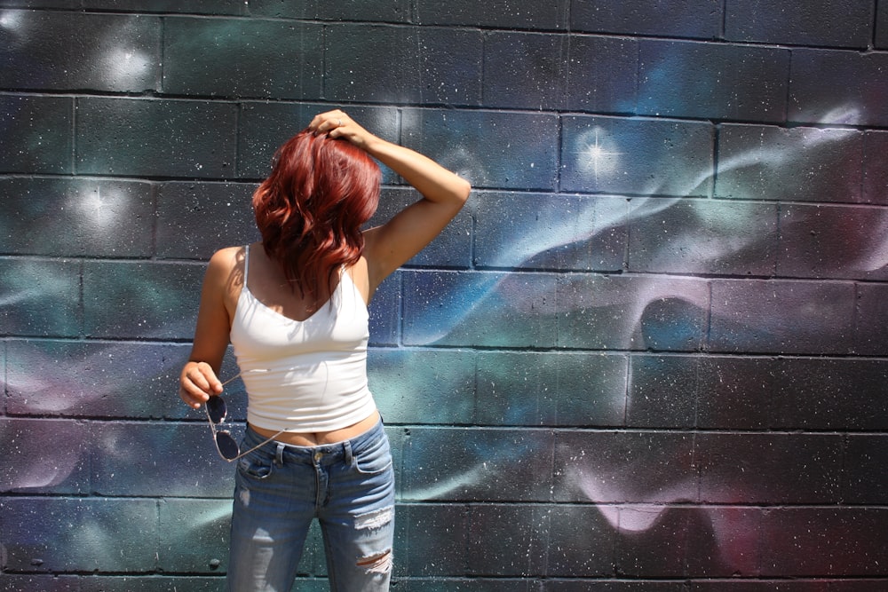 woman wearing white spaghetti-strap top behind wall