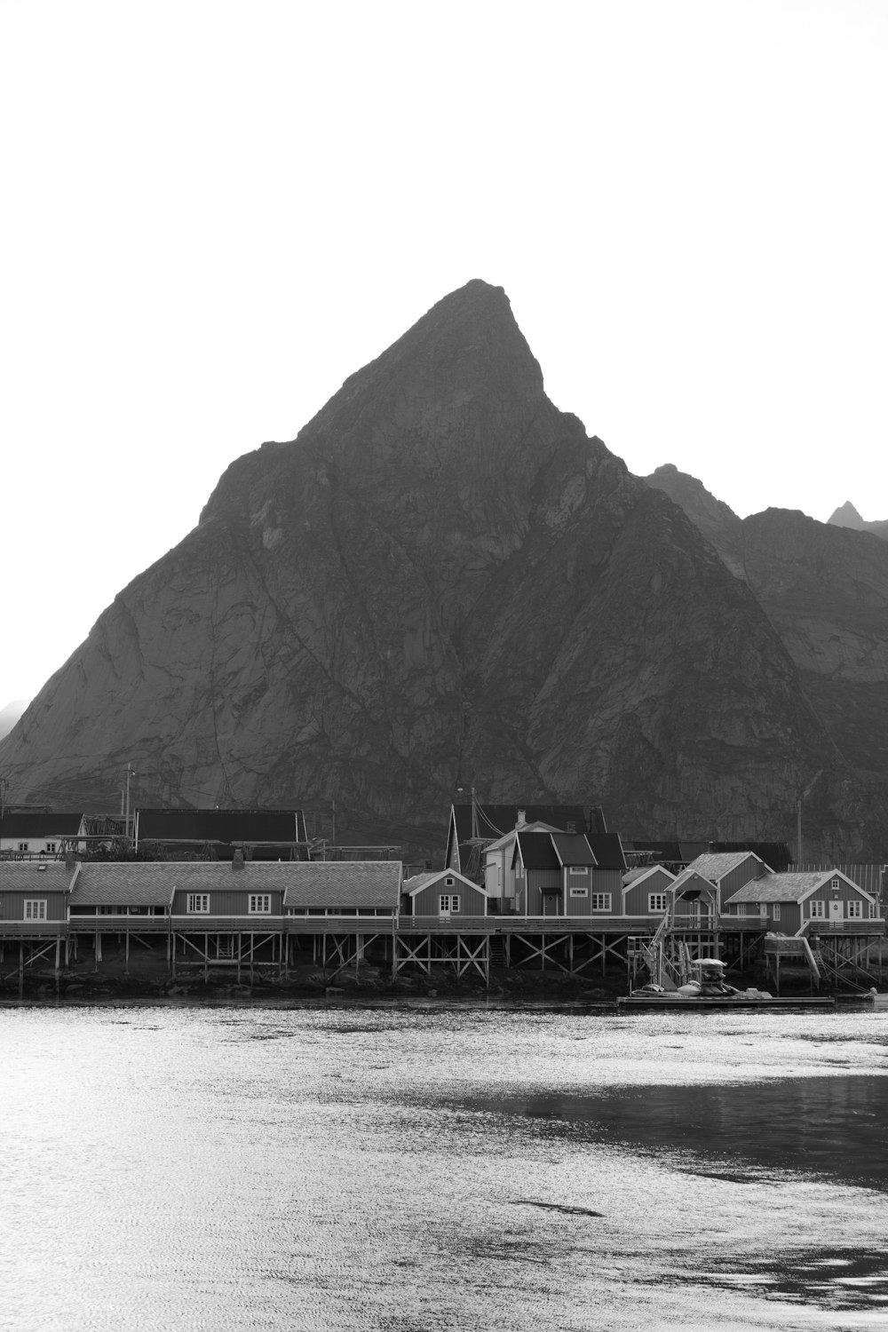 Fotografía en escala de grises de casas bajo el mar junto a las montañas durante el día