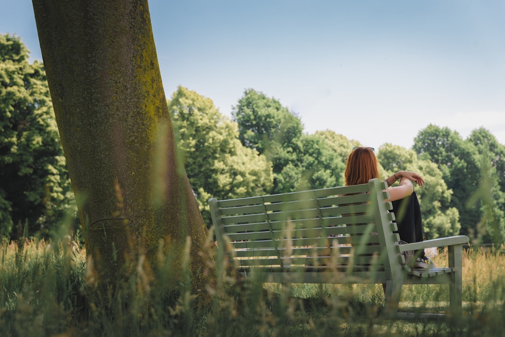 femme assise sur un banc à côté d’un arbre