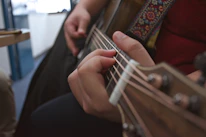Close-up of a musician's hands strumming an acoustic guitar.