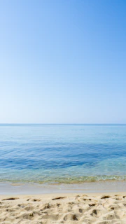 A peaceful beach scene with clear blue waters and soft sand, perfect for relaxation