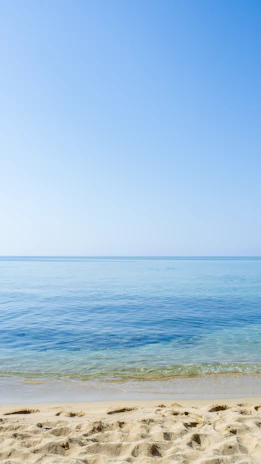 A sunlit beach with turquoise waves gently lapping the shore, inviting relaxation.
