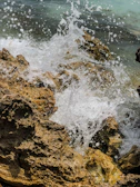 An artistic video still showing waves crashing on a rocky shore.