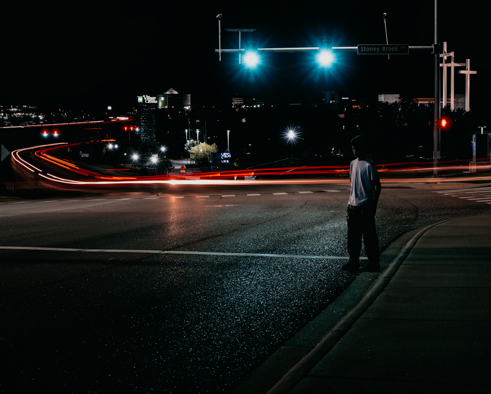 man standing along the road under lights