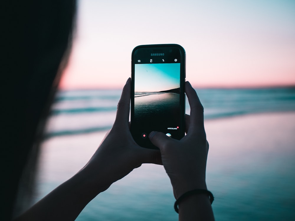 shallow focus photography of person taking photo body of water