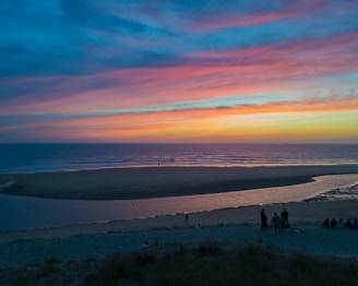 A stunning beach sunset with travelers enjoying the view and taking photos.