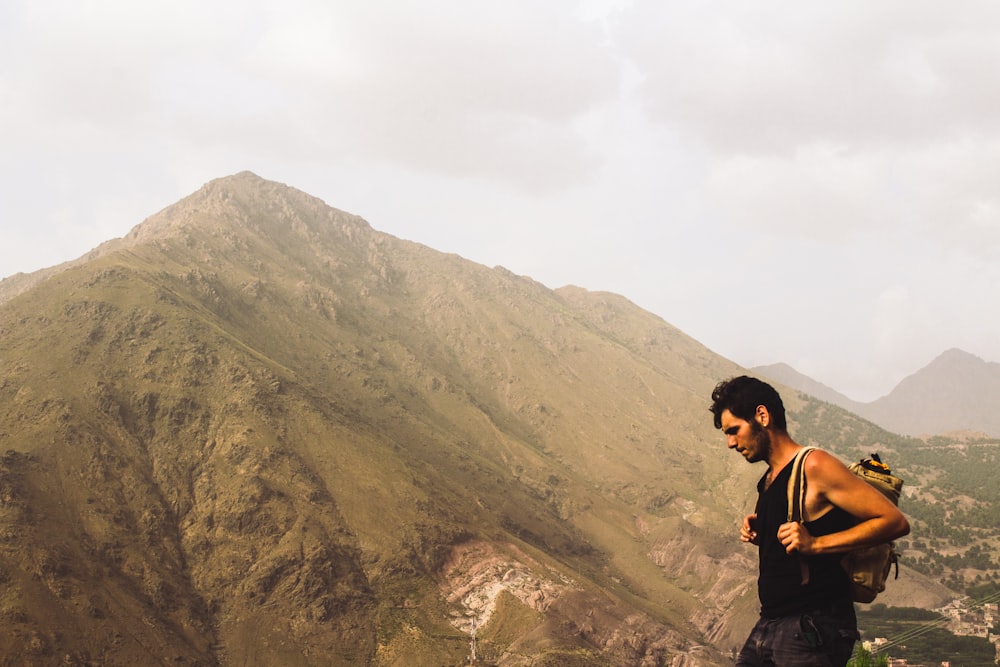homem carregando mochila em pé perto da montanha