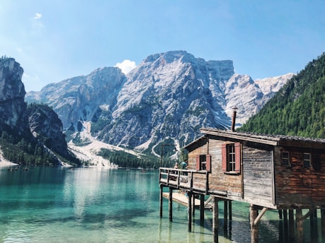 wooden house over body of water near moutain