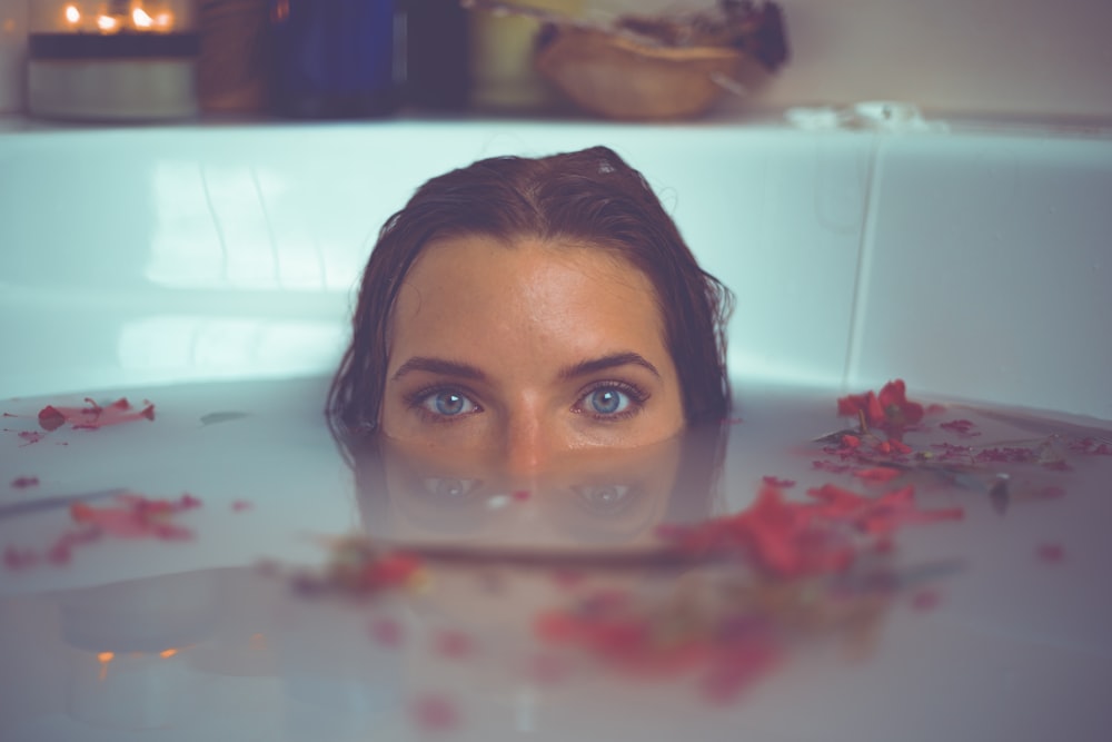 빨간 꽃잎이 물에 떠 있는 욕조에 있는 여자