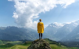 woman standing on rock in front of mountain during daytime