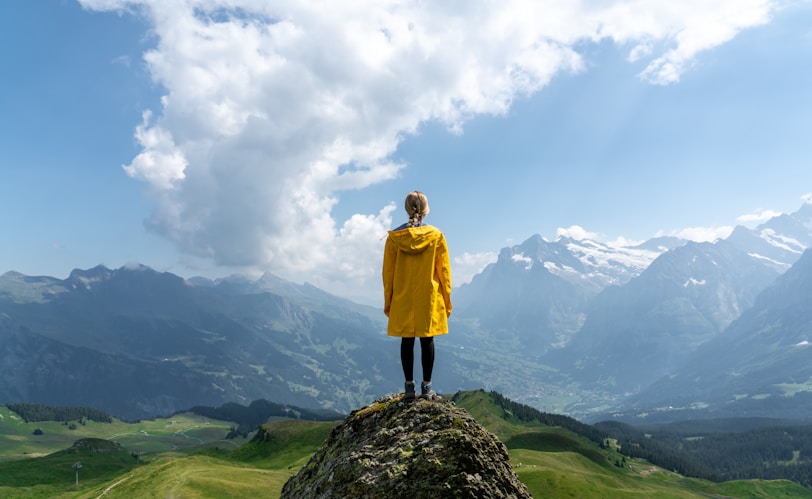 woman standing on rock in front of mountain during daytime