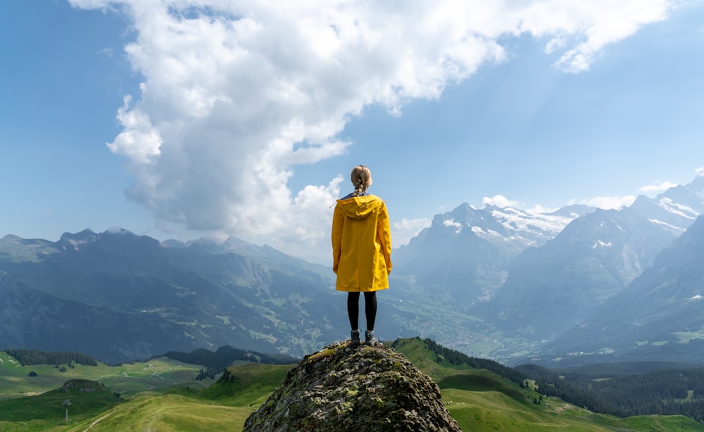 Frau, die tagsüber auf einem Felsen vor dem Berg steht