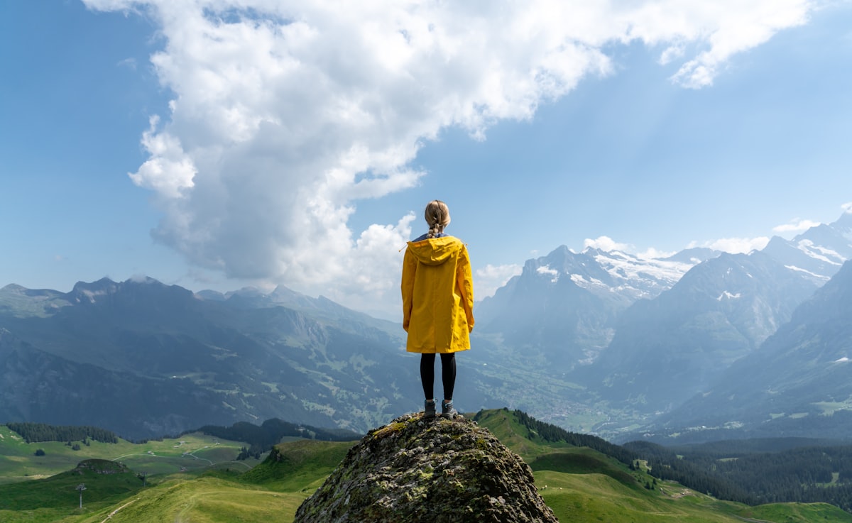 Person standing at a mountain viewpoint overlooking the Swiss Alps