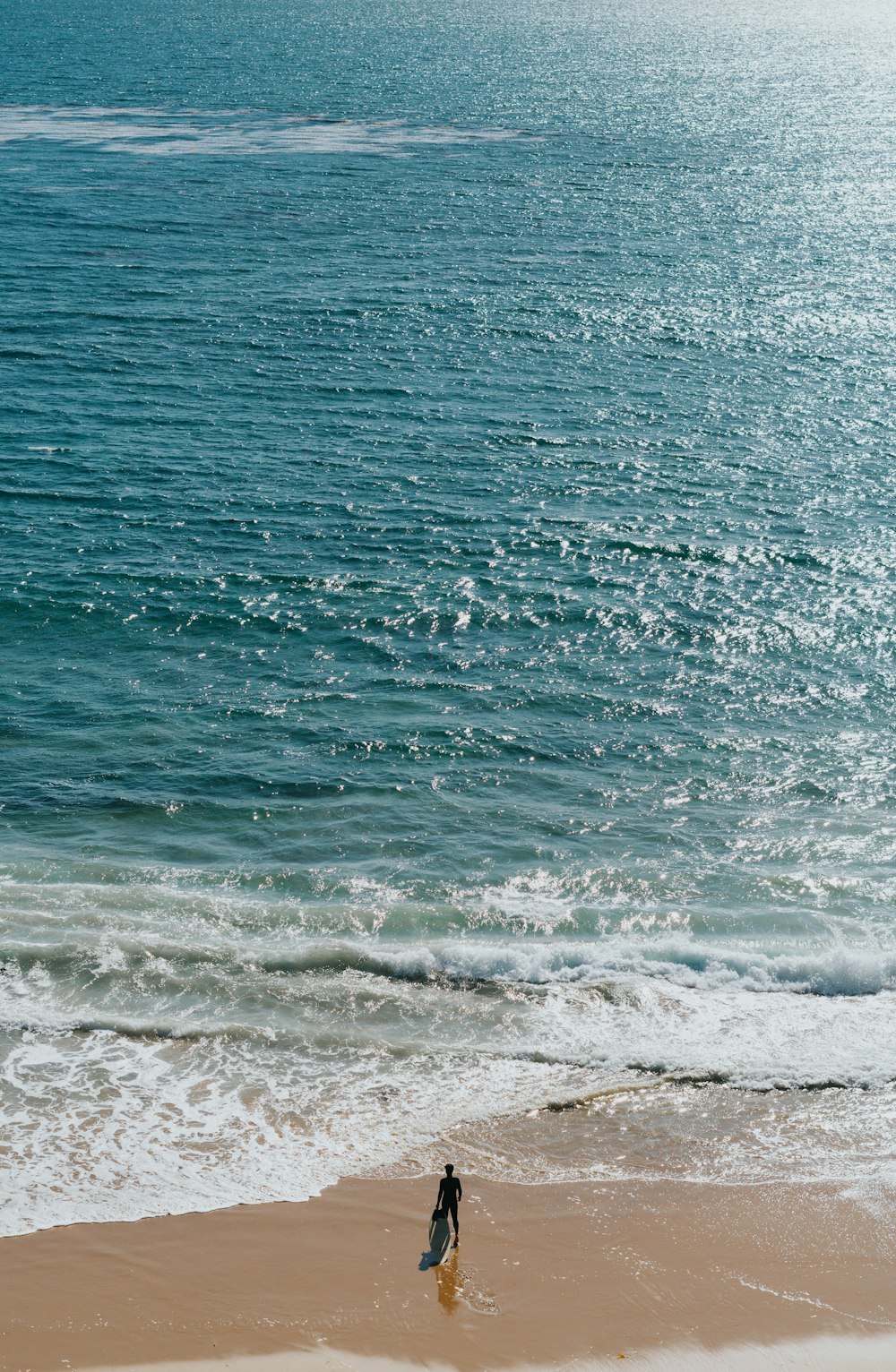 hombre que lleva una tabla de surf en la orilla del mar