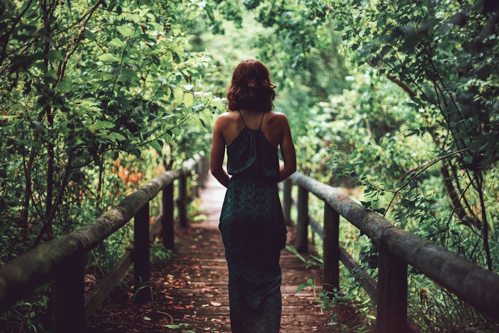 Frau im schwarzen Kleid steht auf Brücke
