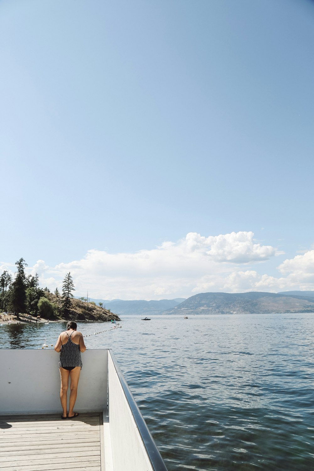 woman standing on dock in front of body of water