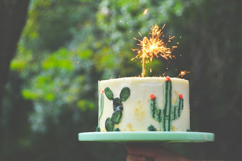 Fotografia a fuoco selettiva della torta bianca e verde con la candela della scintilla