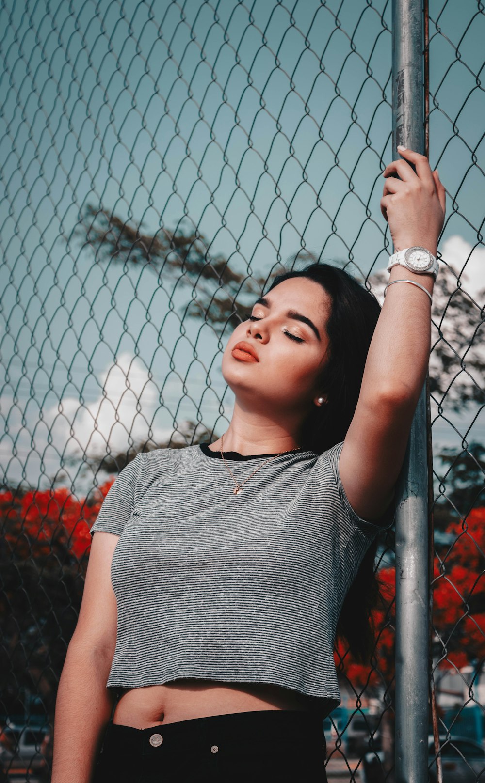 woman wearing gray crew-neck crop top holding gray fence