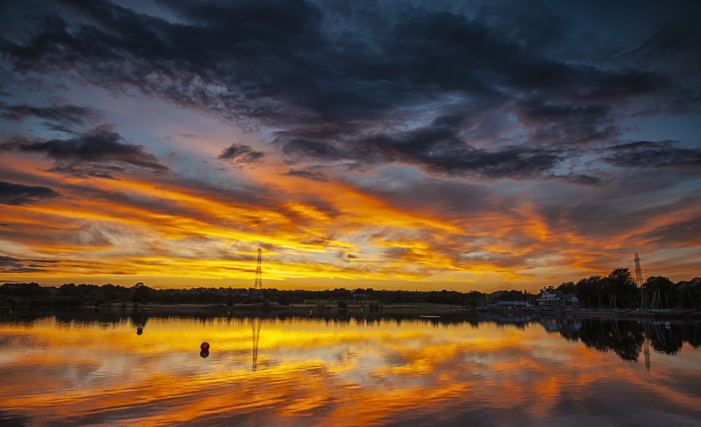 photograph of structures reflecting on body of water during golden hour