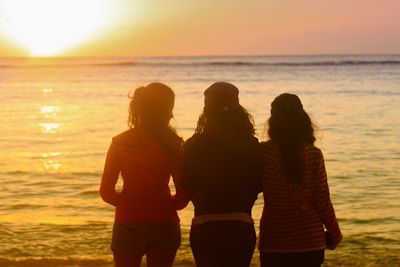 Sunset silhouette of the three friends standing side by side, symbolizing their united journey.
