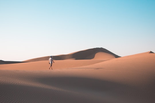 man walking on desert under blue sky during daytime in Isfahan Iran