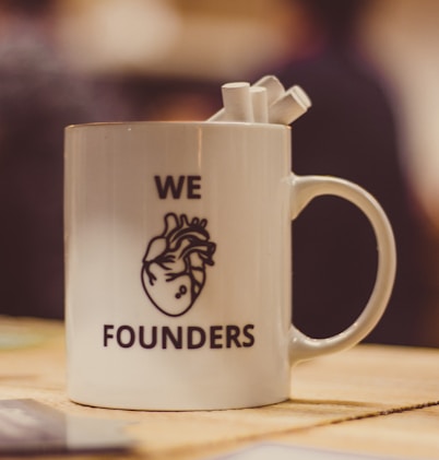 selective focus photo of we Founders heart-printed ceramic mug