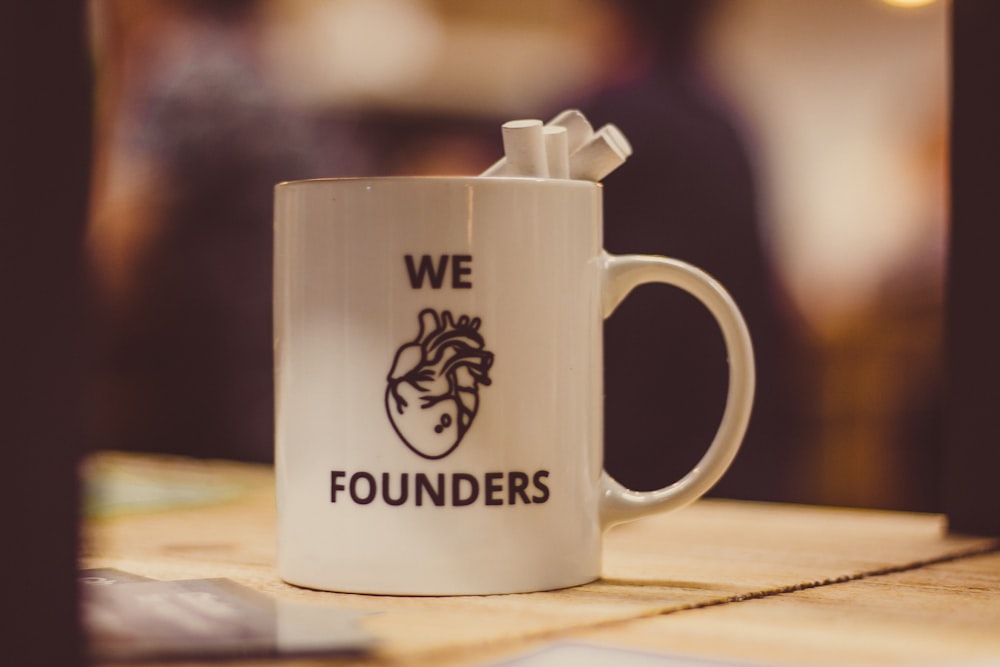 selective focus photo of we Founders heart-printed ceramic mug