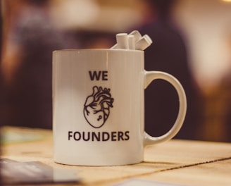 selective focus photo of we Founders heart-printed ceramic mug