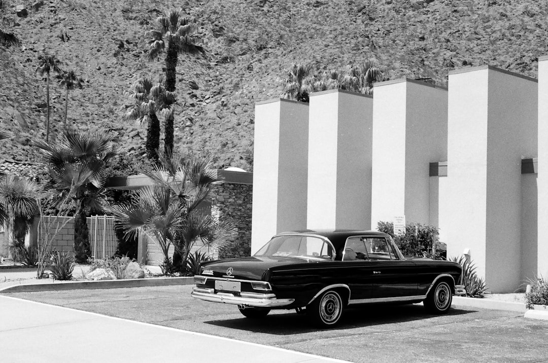 grayscale photography of gray coupe parked in front of white building