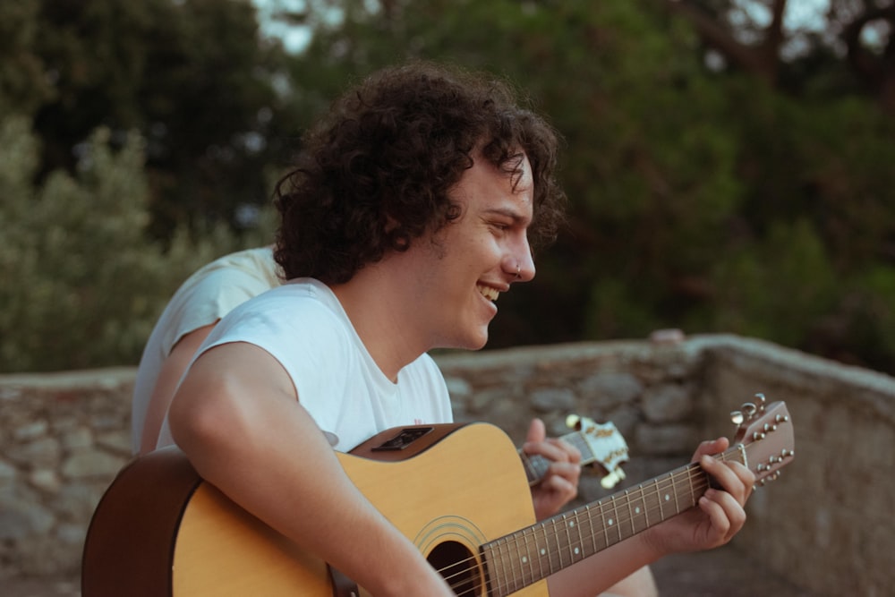 man playing acoustic guitar while smiling