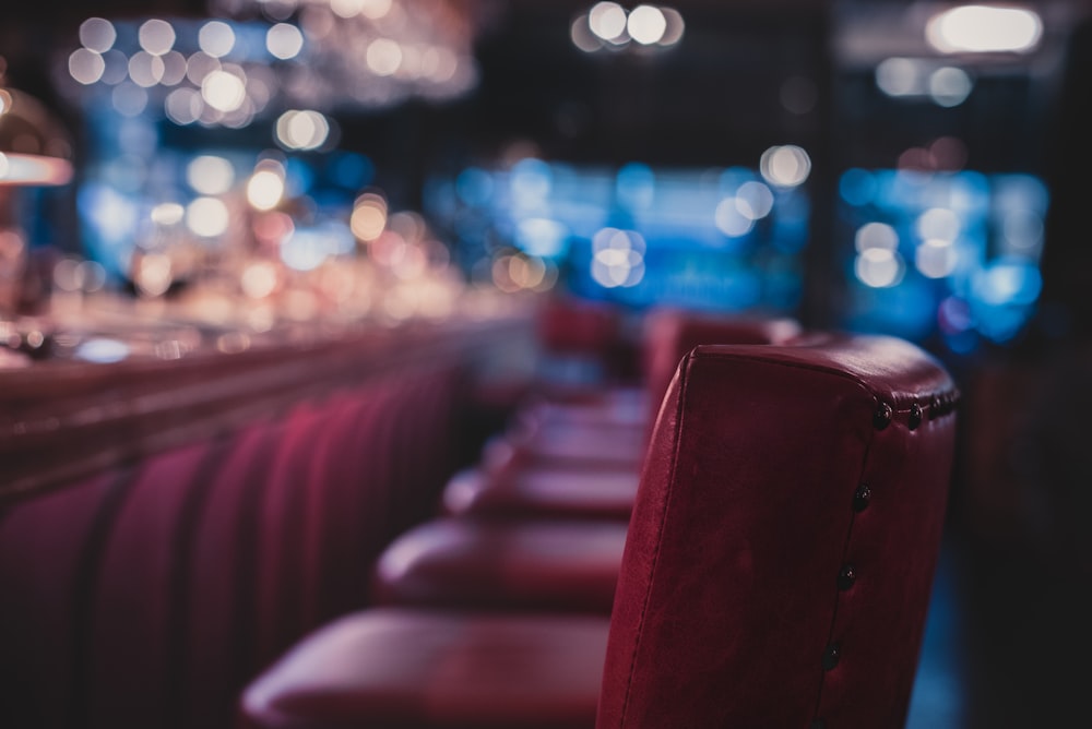 a row of red chairs sitting in front of a bar