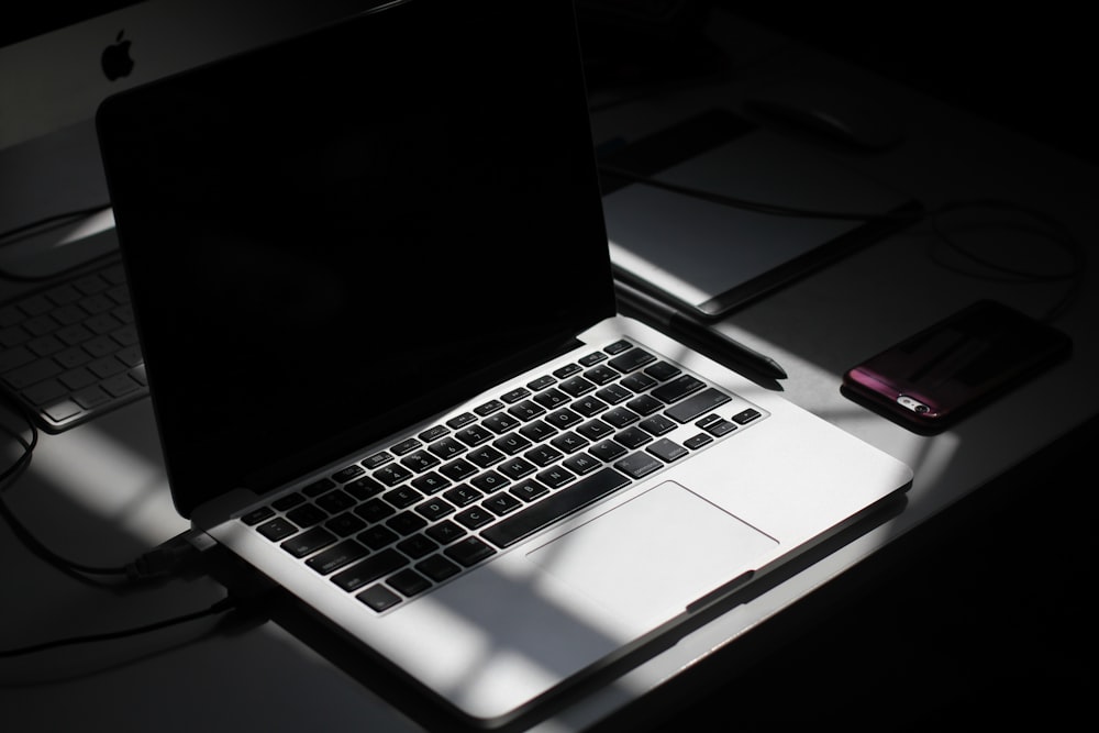 black and silver laptop computer beside smartphone