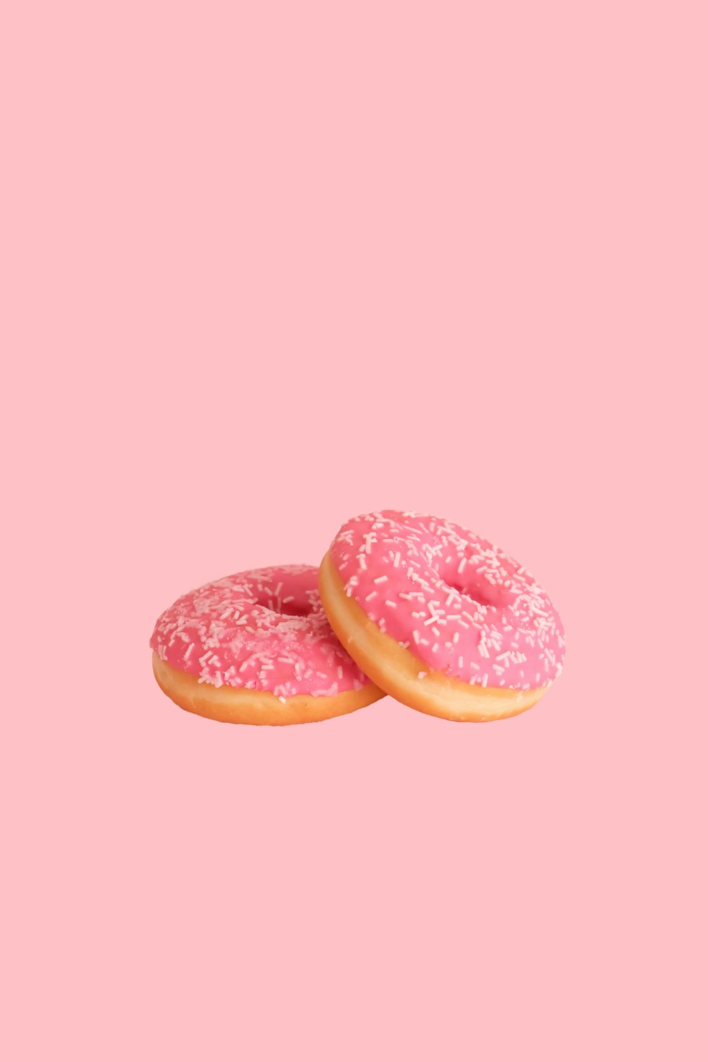 two strawberry doughnuts with sprinkles