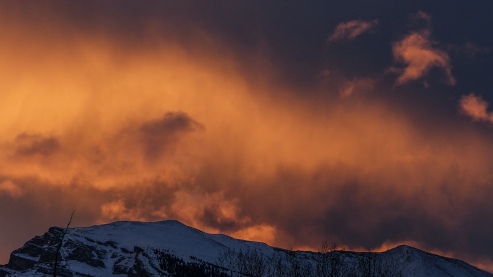 snowy mountain under cloudy sky during sunset