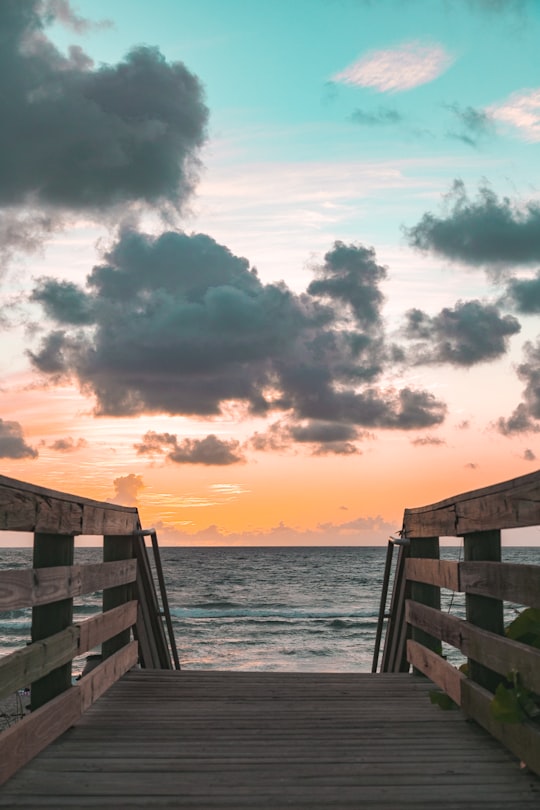 brown wooden stairs in front of water in Juno Beach United States