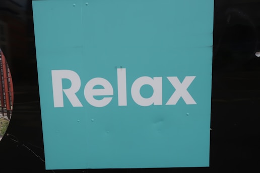 A turquoise square background with the word 'Relax' written in bold, white letters. The background is simple and plain, creating a minimalist appearance.