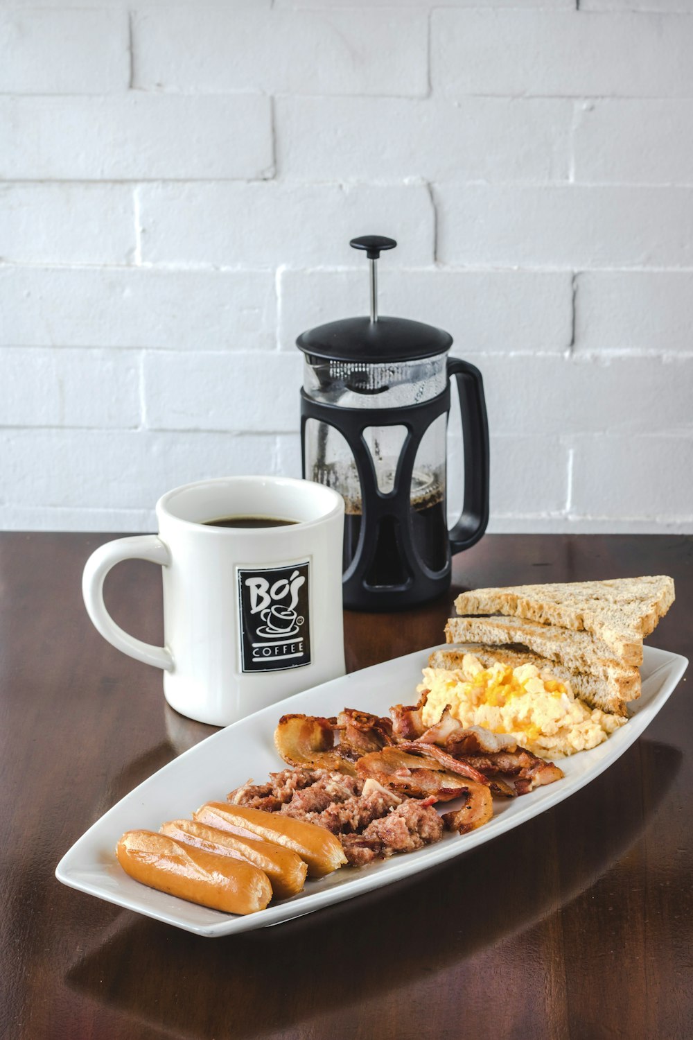 bread and bacon platter beside French press