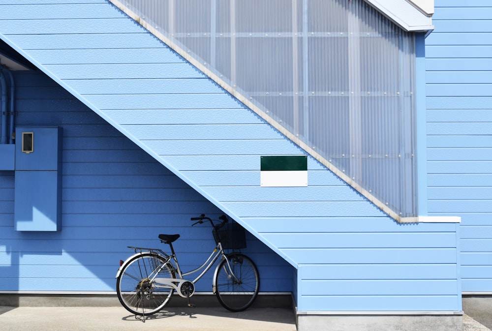 gray bike parked near blue house