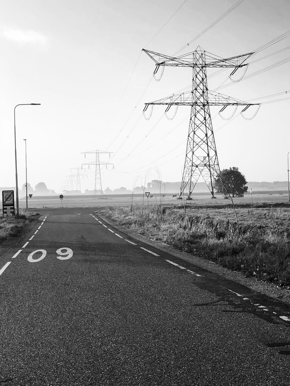 Photographie en niveaux de gris d’une route avec une tour utilitaire