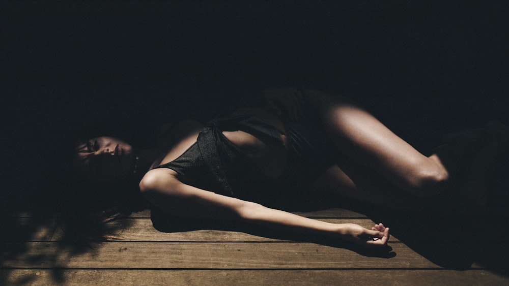 woman lying on brown wooden floor