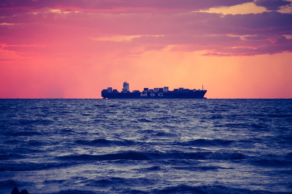 black ship on calm sea during golden hour