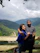 A smiling couple enjoying a cozy balcony view overlooking lush green hills at Shivalik Valley Resort.