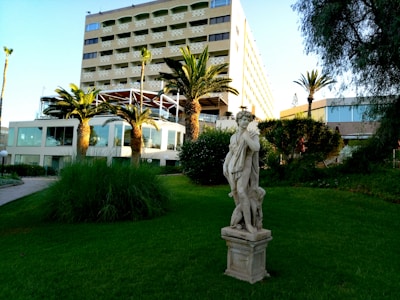 A serene outdoor scene of a classical sculpture garden with greenery.