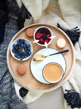 flat lay photography of cup of coffee beside raspberries and blueberries on bowls